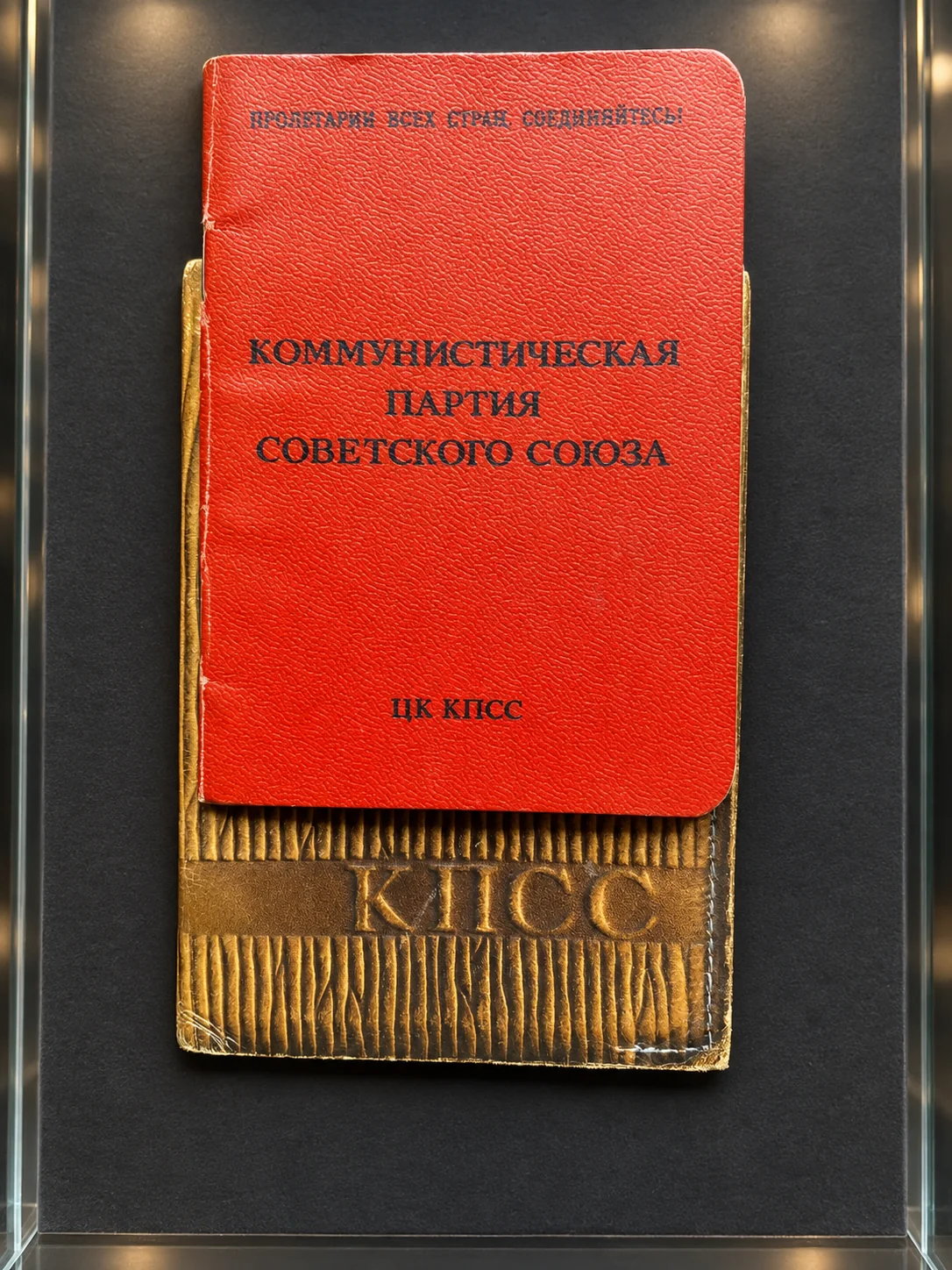 Червона обкладинка партійного квитка КПРС у музейній вітрині